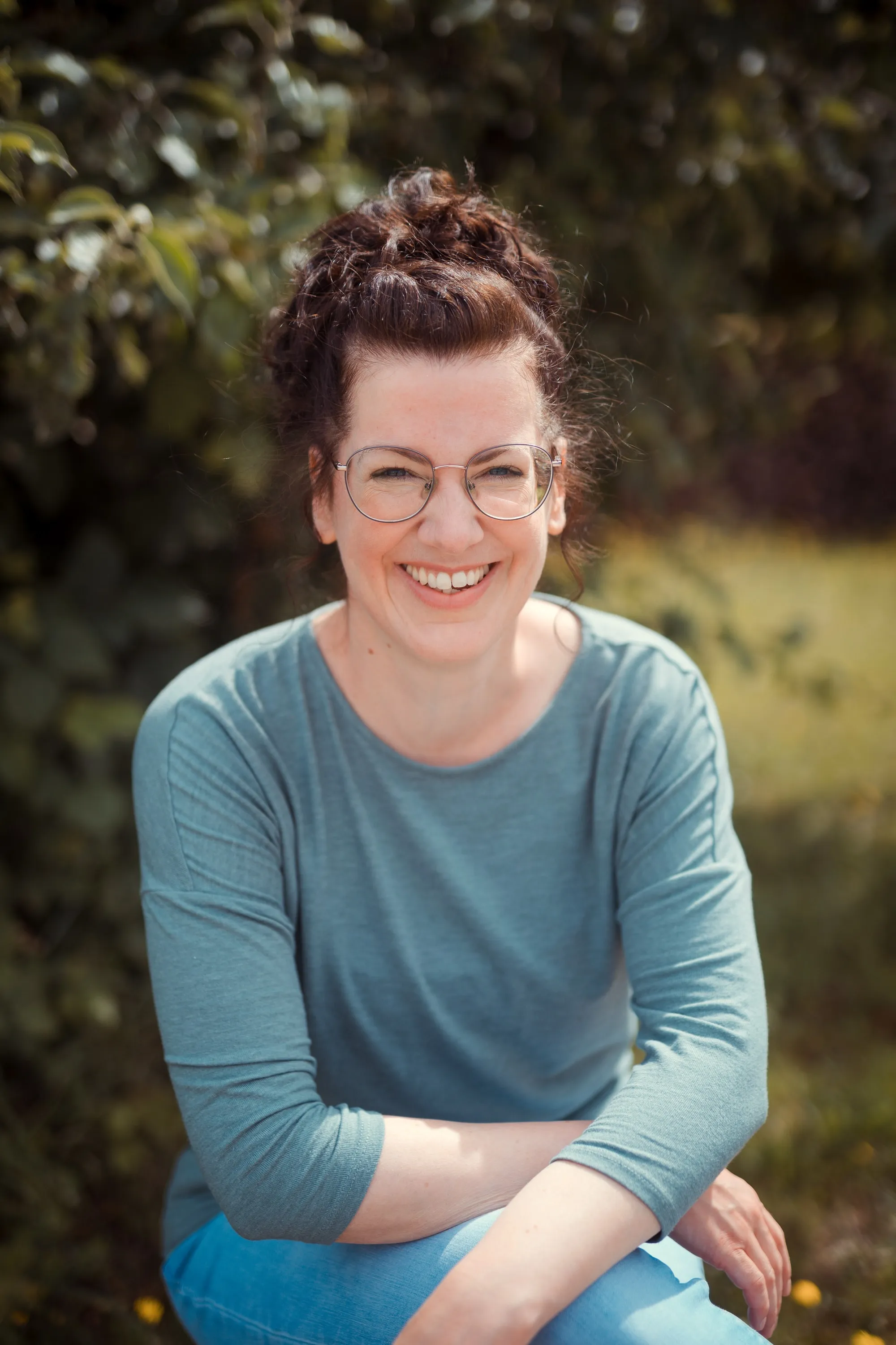 Carolin Reuter, sitzend im Freien, lächelnd
